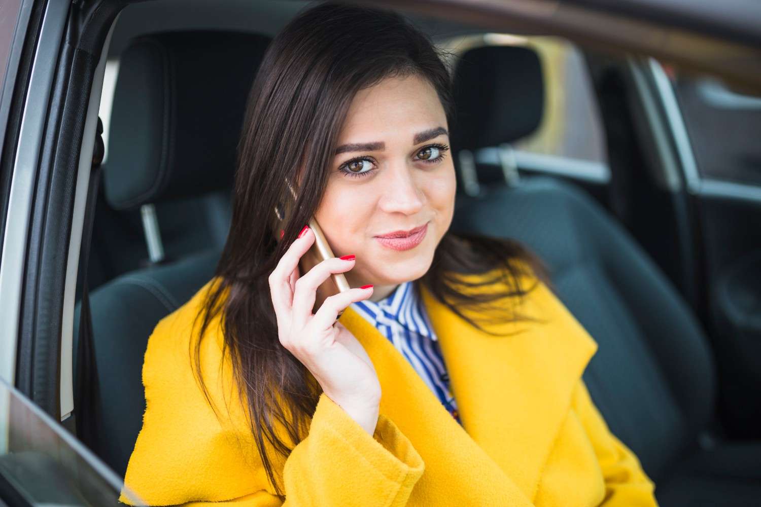 A female passenger talking on her phone while enjoying a relaxed, safe ride in a local cab.