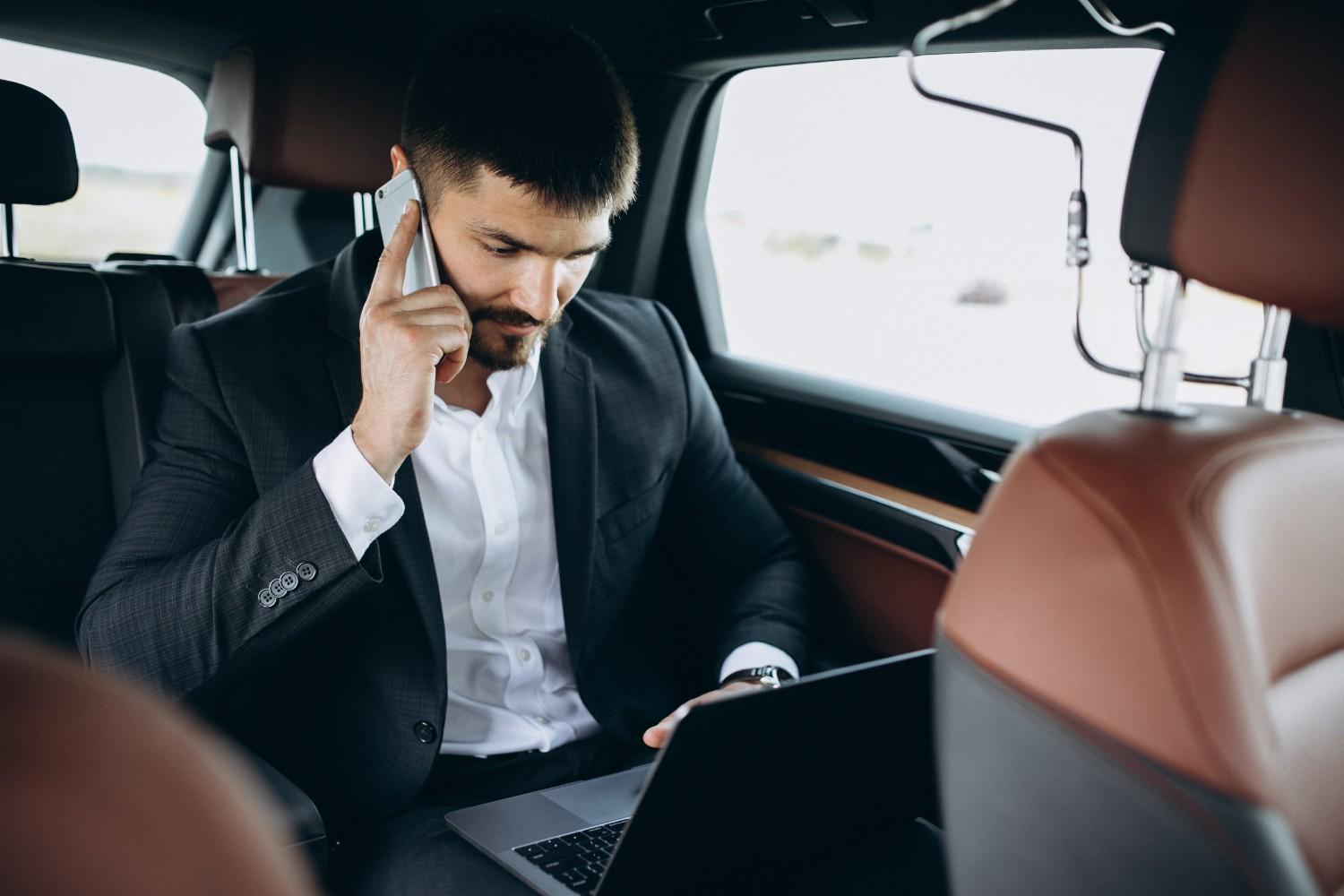 Corporate professional working in the backseat of a luxury airport taxi during a business transfer.